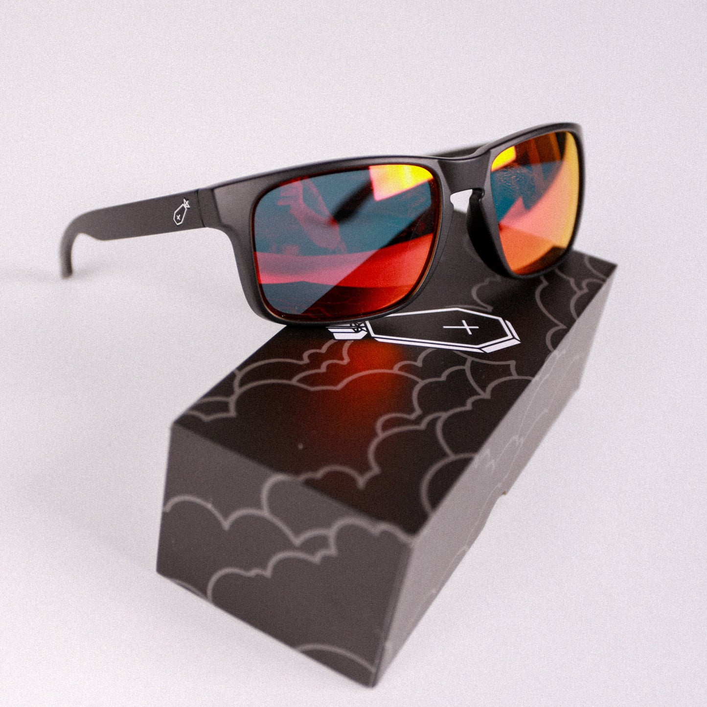 Sunglasses with red-tinted lenses on a black stand with a white background