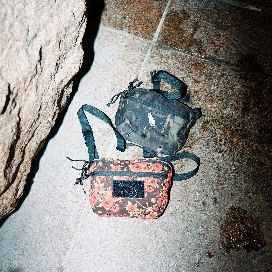 Two bags on a stone floor, one floral and one camouflage.