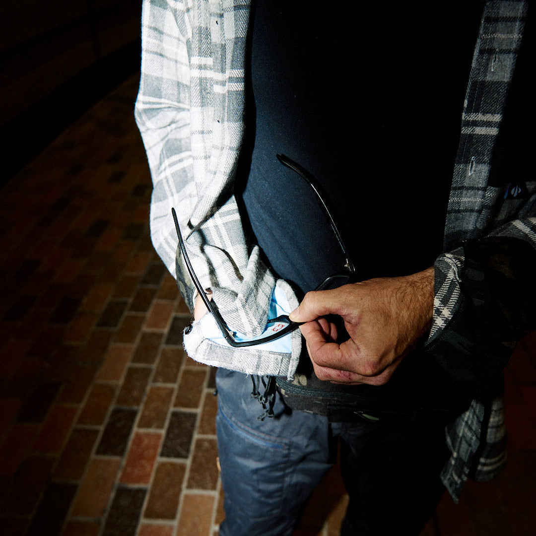 Person holding sunglasses with a dark background