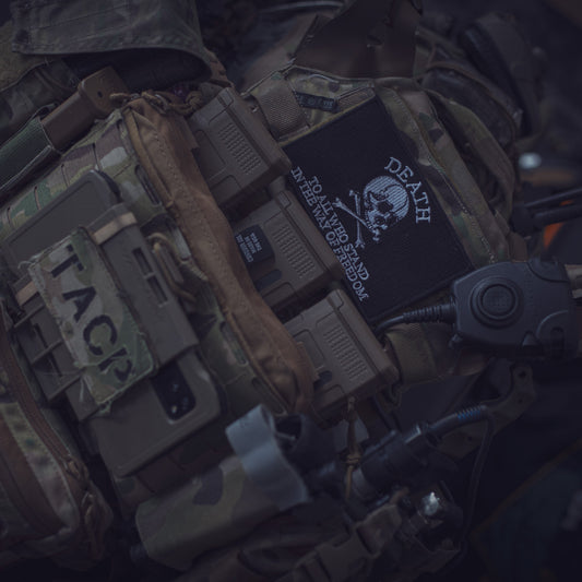 A collection of tactical gear with various patches, including a black flag patch with the word 'DEATH' on it, indicating affiliation or personal interest in a military or special operations theme.